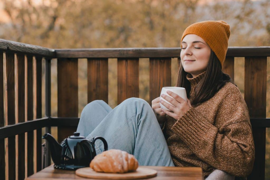 Woman relaxing with tea on cozy balcony