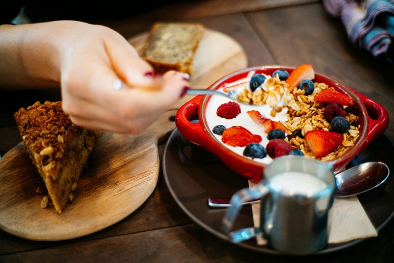 Yogurt with berries and granola, served with cake.