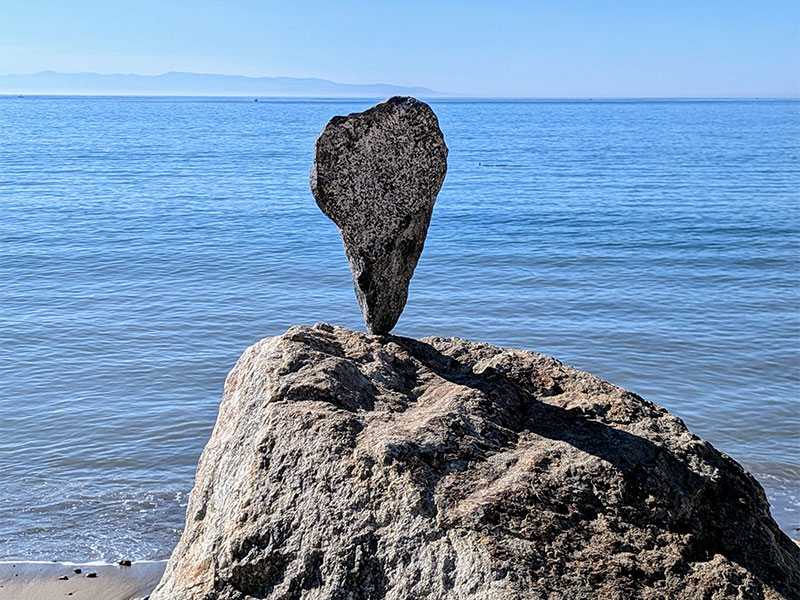 Balancing stone on beach with ocean background